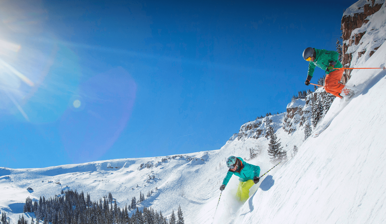 People skiing down steep hill