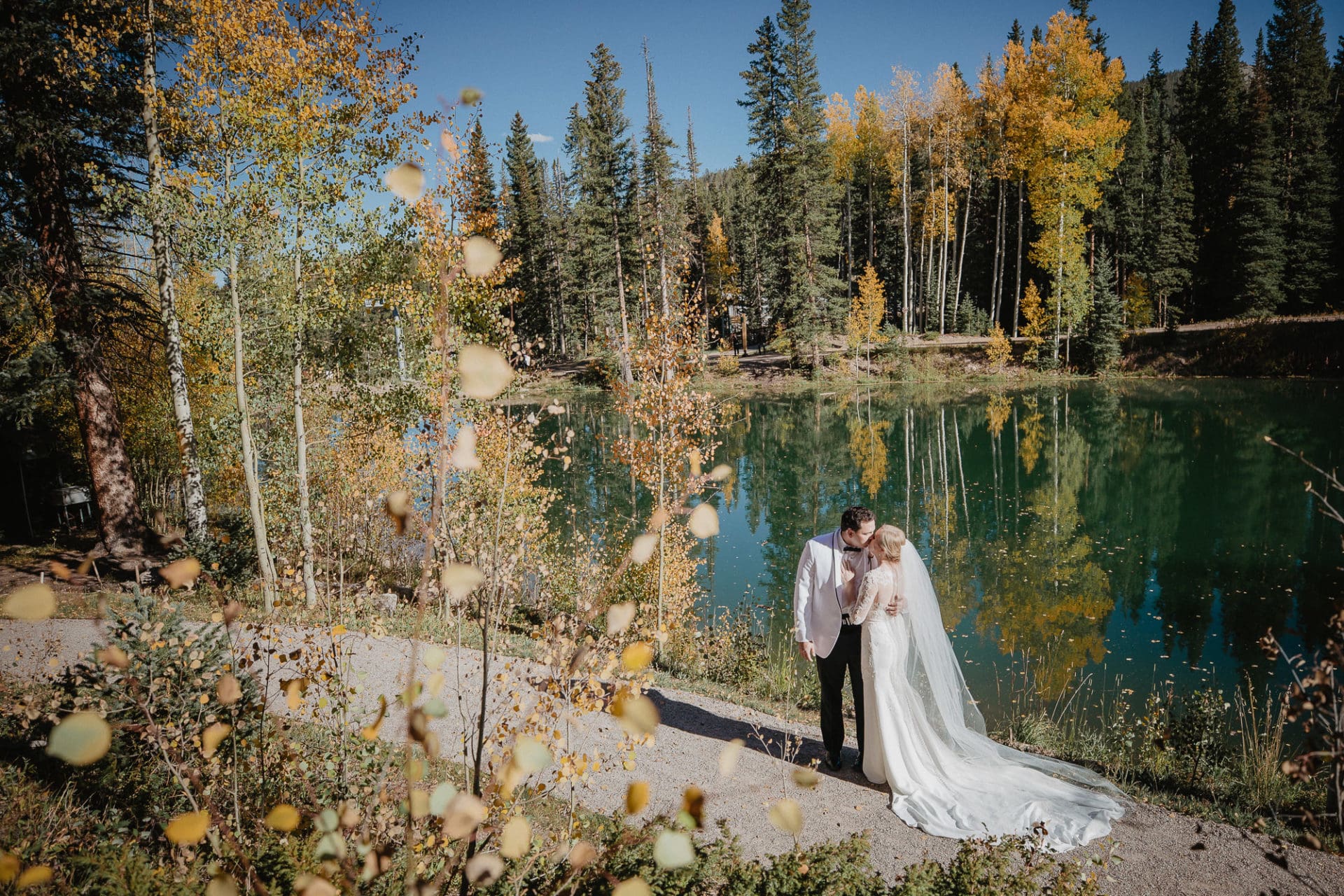 Bride and Groom kissing by a lake during fall